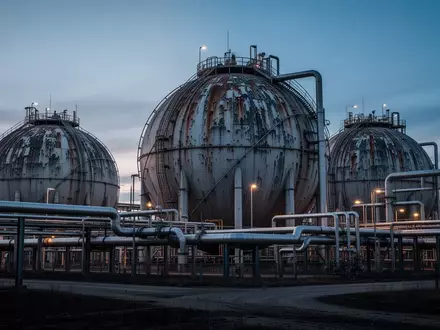 Ein industrielles Erdgasspeicher-Gelände mit großen Kugeltanks und Rohrleitungen in der Dämmerung. - Foto: über boerse-global.de