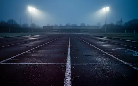 Eine leere, beleuchtete Leichtathletikbahn bei Dämmerung, die die Einsamkeit und den Druck im Leistungssport symbolisiert. - Foto: über boerse-global.de