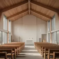 Innenraum einer modernen, schlichten Kirche mit Holzbänken und großen Fenstern bei natürlichem Tageslicht. - Foto: über boerse-global.de
