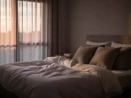 Ein ungemachtes Bett in einem ruhig beleuchteten Schlafzimmer am Morgen, das eine friedliche Atmosphäre vermittelt. - Foto: über boerse-global.de