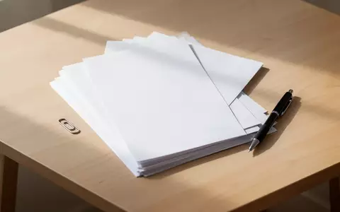 Ein ordentlicher Schreibtisch mit einem Stapel leerer weißer Papierbögen, einer Büroklammer und einem schwarzen Stift. - Foto: über boerse-global.de