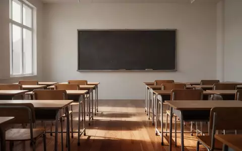 Ein leerer, minimalistischer Klassenraum mit ordentlich aufgereihten Holztischen und Stühlen vor einer leeren Wandtafel. - Foto: über boerse-global.de