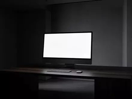 Ein minimalistischer Arbeitsplatz mit einem ausgeschalteten Monitor in einem abgedunkelten Raum. - Foto: über boerse-global.de