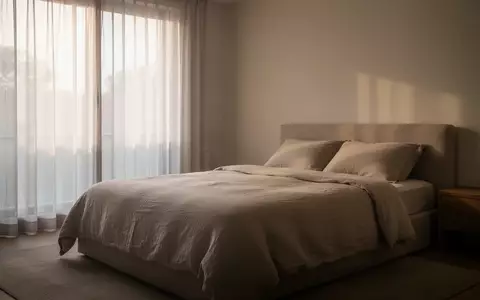 Ein minimalistisch eingerichtetes, ruhiges Schlafzimmer mit einfallendem Tageslicht und einem unbesetzten, ordentlich gemachten Bett. - Foto: über boerse-global.de