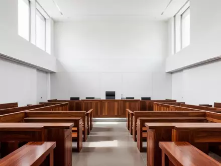 Ein minimalistischer, heller Gerichtssaal mit Holzbänken und natürlichem Lichteinfall. - Foto: über boerse-global.de