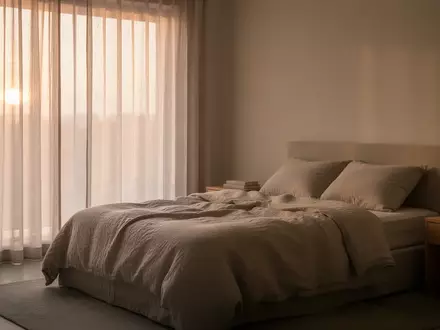 Ein minimalistisch eingerichtetes, ruhiges Schlafzimmer bei Tagesanbruch mit weichem, natürlichem Licht. - Foto: über boerse-global.de
