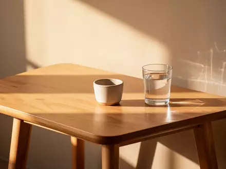 Ein minimalistischer Holztisch mit einem leeren Blumentopf und einem Glas Wasser in sanftem Morgenlicht. - Foto: über boerse-global.de