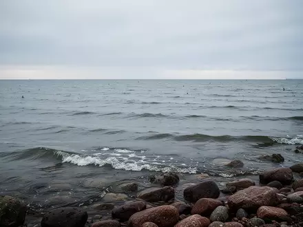 Die ruhige, weite Ostsee unter einem bewölkten Himmel mit sanften Wellen, die an eine natürliche Felsküste branden. - Foto: über boerse-global.de