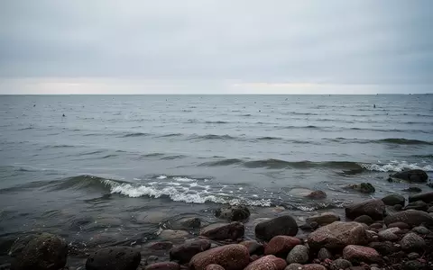 Die ruhige, weite Ostsee unter einem bewölkten Himmel mit sanften Wellen, die an eine natürliche Felsküste branden. - Foto: über boerse-global.de