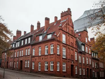 Reihenhauszeile aus rotem Backstein in einer deutschen Stadt bei bewölktem Herbstwetter. - Foto: über boerse-global.de