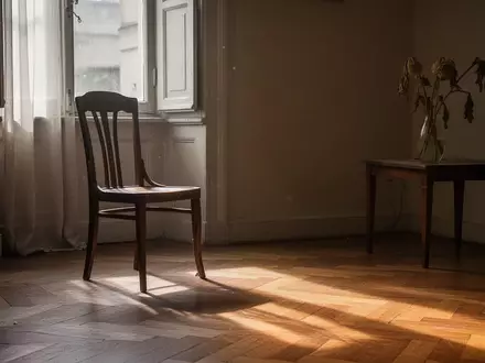 Ein leerer Holzstuhl in einem sonnendurchfluteten Raum mit einer Blumenvase auf einem Beistelltisch. - Foto: über boerse-global.de