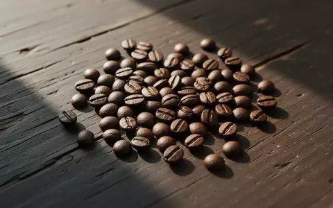 Geröstete Kaffeebohnen auf einer dunklen Holzoberfläche im natürlichen Licht. - Foto: über boerse-global.de