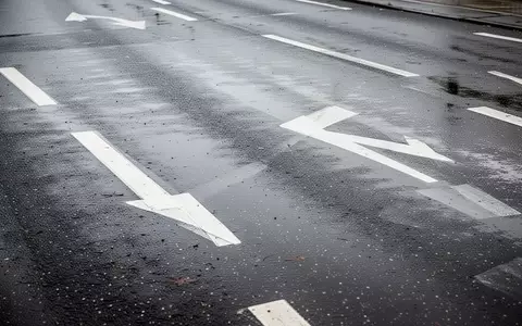 Nasser Asphalt mit weiĂen Fahrbahnmarkierungen auf einer StraĂe bei bewölktem Tageslicht. - Foto: ĂŒber boerse-global.de