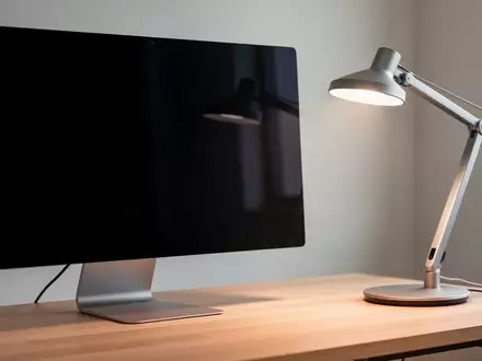 Ein moderner, aufgeräumter Arbeitsplatz mit einem dunklen, ausgeschalteten Monitor und einer Schreibtischlampe. - Foto: über boerse-global.de