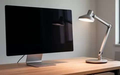 Ein moderner, aufgeräumter Arbeitsplatz mit einem dunklen, ausgeschalteten Monitor und einer Schreibtischlampe. - Foto: über boerse-global.de