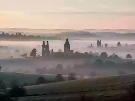 Morgenstimmung mit nebliger Hügellandschaft und den Silhouetten alter Kirchtürme in der Ferne - Foto: über boerse-global.de