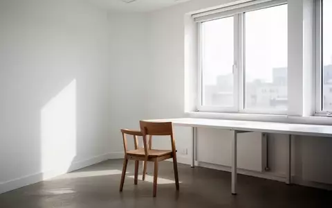Ein minimalistischer, heller Raum mit einem leeren Stuhl und einem leeren Schreibtisch vor einem Fenster. - Foto: über boerse-global.de