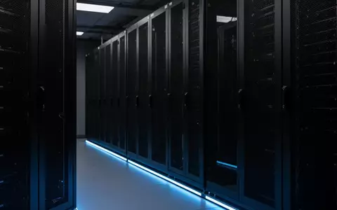 Ein minimalistischer, dunkel gehaltener Serverraum mit symmetrischen schwarzen Rack-Reihen und dezenter blauer Beleuchtung. - Foto: über boerse-global.de
