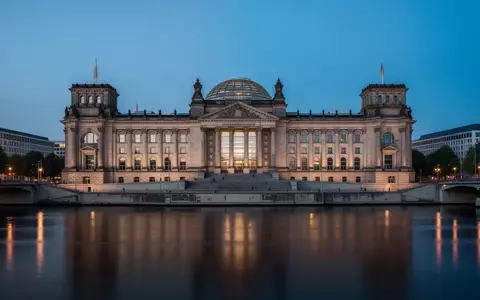 Das Reichstagsgebäude in Berlin in der Dämmerung, aufgenommen von der Spree aus mit Fokus auf die Architektur. - Foto: über boerse-global.de