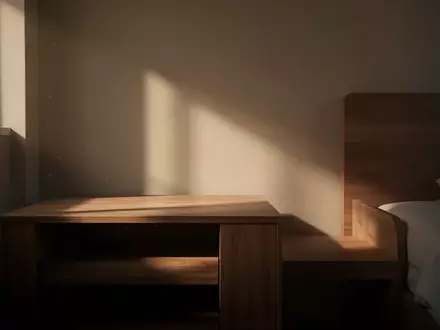 Ein schlichtes, ruhig wirkendes Schlafzimmer mit einem leeren Nachttisch im gedämpften Morgenlicht. - Foto: über boerse-global.de