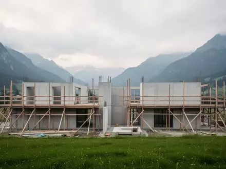 Baustelle für ein Wohnbauprojekt in einer Schweizer Hügellandschaft mit Betonstrukturen und Gerüsten. - Foto: über boerse-global.de