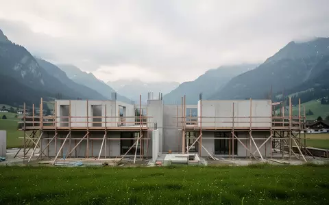 Baustelle für ein Wohnbauprojekt in einer Schweizer Hügellandschaft mit Betonstrukturen und Gerüsten. - Foto: über boerse-global.de