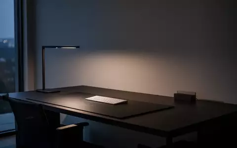 Ein minimalistisch gestalteter, aufgeräumter Schreibtisch in einem modernen Büro bei Dämmerung mit atmosphärischer Beleuchtung. - Foto: über boerse-global.de