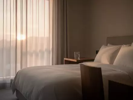 Ein minimalistisch eingerichtetes Schlafzimmer in den frĂĽhen Morgenstunden mit sanftem, natĂĽrlichem Licht. - Foto: ĂĽber boerse-global.de