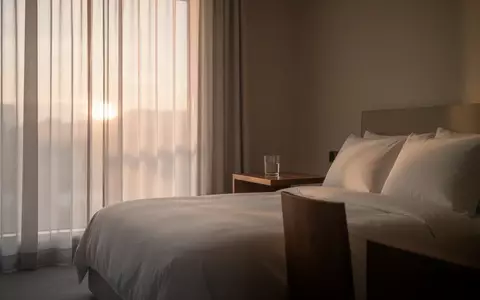 Ein minimalistisch eingerichtetes Schlafzimmer in den frühen Morgenstunden mit sanftem, natürlichem Licht. - Foto: über boerse-global.de