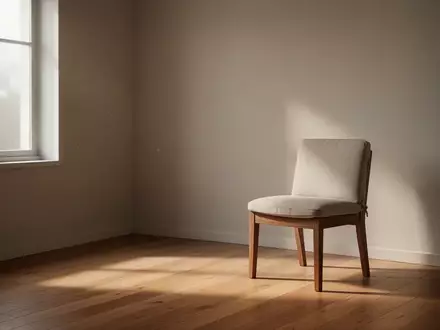 Ein minimalistischer, ruhiger Therapieraum mit sanftem Tageslicht und einem schlichten Stuhl vor einer leeren Wand. - Foto: über boerse-global.de