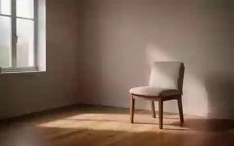 Ein minimalistischer, ruhiger Therapieraum mit sanftem Tageslicht und einem schlichten Stuhl vor einer leeren Wand. - Foto: über boerse-global.de