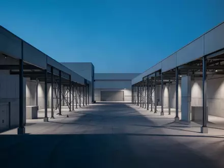 Eine weite, minimalistische Industrieanlage bei Dämmerung mit klaren architektonischen Linien und geometrischen Schatten. - Foto: über boerse-global.de
