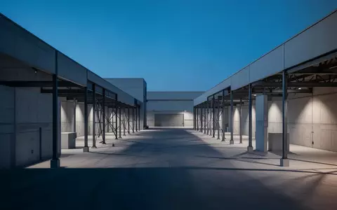 Eine weite, minimalistische Industrieanlage bei Dämmerung mit klaren architektonischen Linien und geometrischen Schatten. - Foto: über boerse-global.de