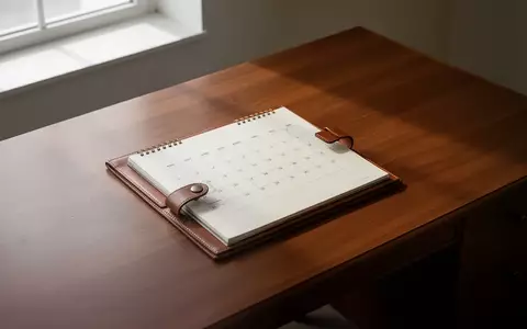 Ein leerer, aufgeräumter Schreibtisch mit einem ledergebundenen Kalender in sanftem Tageslicht. - Foto: über boerse-global.de