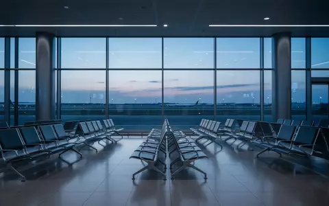 Ein moderner, menschenleerer Flughafen-Warteraum mit großen Fensterfronten bei Dämmerung. - Foto: über boerse-global.de