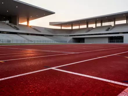 Leere Laufbahn eines modernen Sportstadions bei Dämmerung mit Fokus auf die Textur der Kunststoffbahn. - Foto: über boerse-global.de