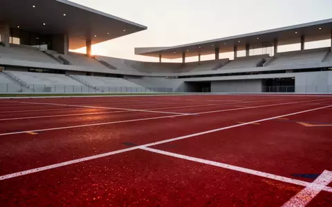 Leere Laufbahn eines modernen Sportstadions bei Dämmerung mit Fokus auf die Textur der Kunststoffbahn. - Foto: über boerse-global.de