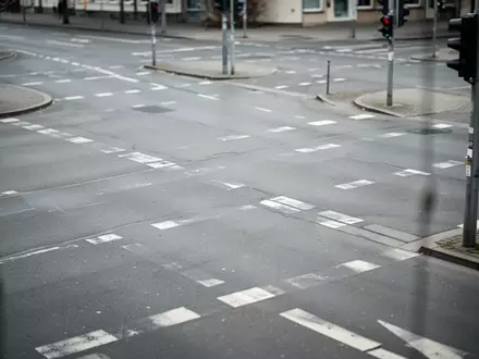 Eine leere, städtische Kreuzung mit Fahrbahnmarkierungen bei bewölktem Tageslicht. - Foto: über boerse-global.de