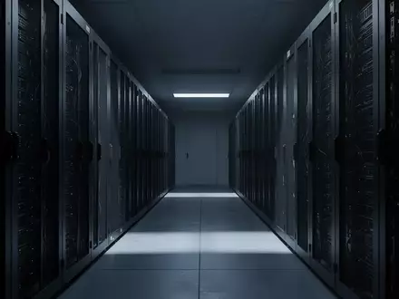 Dunkle, industrielle Server-Racks in einem modernen, sterilen Rechenzentrum mit langen Schattenlinien. - Foto: über boerse-global.de