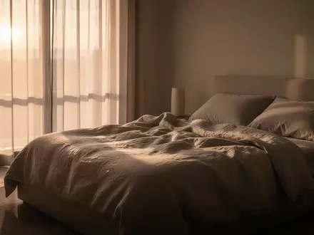 Ein ruhiges Schlafzimmer im sanften Licht der Morgendämmerung mit ungemachtem Bett und neutraler Bettwäsche. - Foto: über boerse-global.de