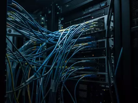 Dunkle, technologische Umgebung mit miteinander verbundenen Kabeln und Serverkomponenten in einem gesicherten Rechenzentrum. - Foto: über boerse-global.de