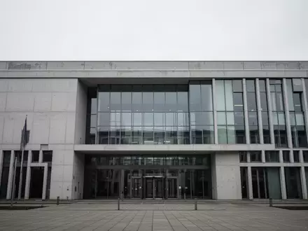 Moderne Fassade eines deutschen Gerichtsgebäudes aus Beton und Glas bei bewölktem Himmel. - Foto: über boerse-global.de