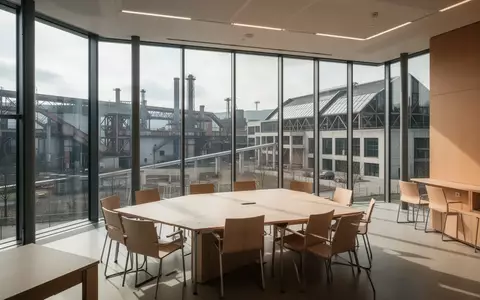 Ein leerer, modern gestalteter Konferenzraum mit bodentiefen Fenstern und Blick auf eine Industriekulisse in Belval. - Foto: über boerse-global.de