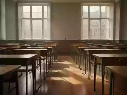 Ein leerer, sonnendurchfluteter Hörsaal mit hölzernen Schreibtischreihen in einer ruhigen Universitätsumgebung. - Foto: über boerse-global.de