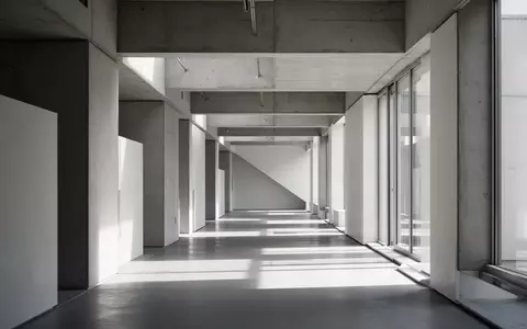 Ein minimalistischer, moderner Flur mit klaren architektonischen Linien und geometrischem Schattenwurf bei natürlichem Licht. - Foto: über boerse-global.de