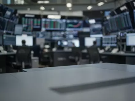 Ein unscharfer Börsenhandelssaal mit einem leeren Schreibtisch im Vordergrund. - Foto: über boerse-global.de