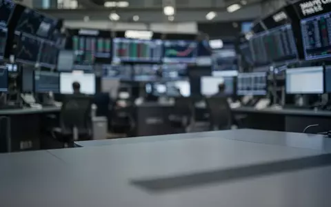 Ein unscharfer Börsenhandelssaal mit einem leeren Schreibtisch im Vordergrund. - Foto: über boerse-global.de