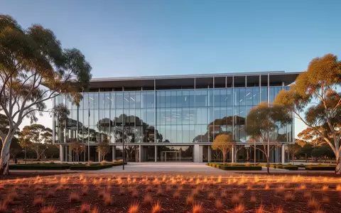 Ein modernes, minimalistisches Regierungsgebäude aus Glas und Stahl in Canberra bei Sonnenuntergang, umgeben von Eukalyptusbäumen. - Foto: über boerse-global.de