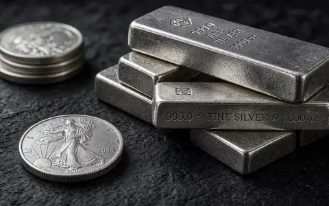 Gestapelte Silberbarren und Silbermünzen auf einer dunklen Schieferplatte bei natürlichem Licht. - Foto: über boerse-global.de