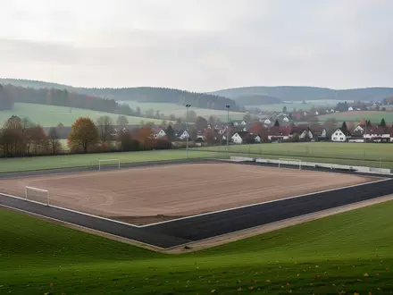 Ein vorbereiteter Sportplatzbau auf einer grünen Wiese in einer ländlichen Umgebung in Nordrhein-Westfalen. - Foto: über boerse-global.de